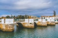 The Roman bridge in Tavira, Portugal, with white railings and stone arches, crossing over a calm river Royalty Free Stock Photo