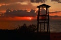 Tawny cloudy sunset silhouetting life guard post watch tower