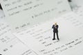Tax, accounting and business expenses concept, miniature businessman figure standing on printed payment invoice or receipt around