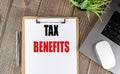 TAX BENEFITS text on clipboard paper with laptop, mouse and pen Royalty Free Stock Photo