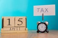 Tax Day Reminder Concept. 15 april wooden calendar and alarm clock with banner and handwritten phrase