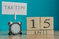 Tax Day Reminder Concept. 15 april wooden calendar and alarm clock with banner and handwritten phrase