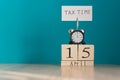 Tax Day Reminder Concept. 15 april wooden calendar and alarm clock with banner and handwritten phrase