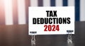 TAX DEDUCTIONS 2024 sign on paper on dark desk in sunlight. Blue and white background Royalty Free Stock Photo