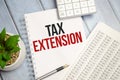 TAX EXTENSION text on paper with calculator, notepad and charts