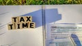 Tax-filling concept - Tax time text on wooden blocks with the U.S IRS 1040 form, notepad and pen background