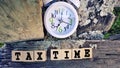 Tax-filling concept - Tax time words on wooden blocks with clock background