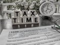 Tax-filling concept - Tax time words on wooden blocks with the U.S IRS 1040 form and clock in vintage background