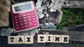 Tax-filling concept - Tax time words on wooden blocks with calculator background