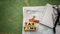 Tax-filling concept - Tax time words on wooden blocks with the U.S IRS 1040 form,coins,notebook,pen and eyeglasses in vintage