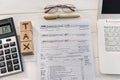 1040 tax form with dollar, laptop and wooden cubes