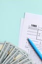 1065 tax form lies near hundred dollar bills and blue pen on a light blue background. US Return for parentship income Royalty Free Stock Photo