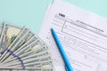 1065 tax form lies near hundred dollar bills and blue pen on a light blue background. US Return for parentship income Royalty Free Stock Photo