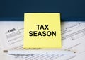 Tax form 1065 with yellow sticker with text Tax Season. Notepad and white pen