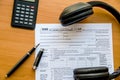 Tax forms 1040, calculator, pen and headphones on a wooden table