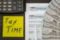 Tax forms 1040 with dollars, sticker, pen and calculator on a black wood table. Tax time concept. Financial document. Royalty Free Stock Photo