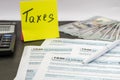 Tax forms 1040 with dollars, sticker, pen and calculator on a black wood table. Tax time concept. Financial document. Royalty Free Stock Photo