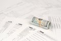 Tax forms lies near roll of hundred dollar bills. Income tax return Royalty Free Stock Photo
