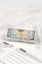 Tax forms lies near roll of hundred dollar bills. Income tax return Royalty Free Stock Photo