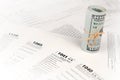 Tax forms lies near roll of hundred dollar bills. Income tax return Royalty Free Stock Photo