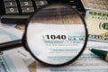 Tax forms 1040 through a magnifier, calculator, dollars and pen on the table Royalty Free Stock Photo