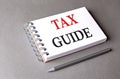 TAX GUIDE word on notebook on grey background