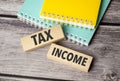 tax income words on wooden blocks with green and yellow notepad