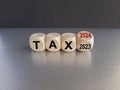 2024 tax new year symbol. Turned a wooden cube and changes words Tax 2023 to Tax 2024. Beautiful grey table black background, copy