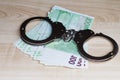 Roll euro money bills on a wooden table in handcuffs. Euro bills with handcuffs. Financial crime, dirty money and corruption Royalty Free Stock Photo