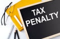 TAX PENALTY text on the blackboard with notepad , pen, pencil Royalty Free Stock Photo