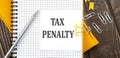 TAX PENALTY text on a sticker on the notebook, wooden background