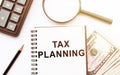 Tax planning word written by notebook on office table with calculator, magnifier, pencil and dollars Royalty Free Stock Photo