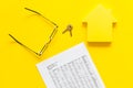 Tax for property accounting with house figure, keys, table, glasses on yellow background top view