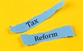 TAX REFORM text on a blue pieces of paper on yellow background, business concept