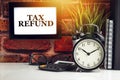 TAX REFUND text with alarm clock, books and vase on brick background Royalty Free Stock Photo