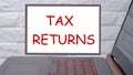 Tax returns a phrase written on a magnetic board next to a laptop with a glowing keyboard