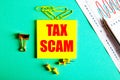 TAX SCAM is written in red on a yellow sticker on a green background near the graph and pencil Royalty Free Stock Photo