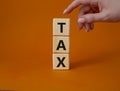 Tax symbol. Wooden cubes with word Tax. Businessman hand. Beautiful orange background. Business and Finace and Tax concept. Copy