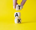 Tax symbol. Wooden cubes with word Tax. Businessman hand. Beautiful yellow background. Business and Finace and Tax concept. Copy