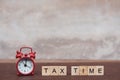 Tax time with Alphabet wooden block cube and Red alarm clock On table dark plank wooden background with copy space Royalty Free Stock Photo