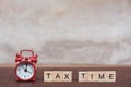 Tax time with Alphabet wooden block cube and Red alarm clock On table dark plank wooden background with copy space Royalty Free Stock Photo