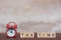 Tax time with Alphabet wooden block cube and Red alarm clock On table dark plank wooden background with copy space Royalty Free Stock Photo