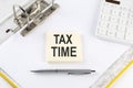 TAX TIME - business concept, message on the sticker on folder background with calculator