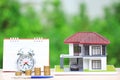 Tax time concept, Model house and car with stacking coins money and alarm clock and calendar on natural green background
