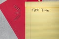 Tax time handwritten on a yellow legal lined notepad