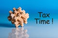 Tax time - message on blue background with wooden brain teaser Royalty Free Stock Photo