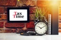 TAX TIME text with alarm clock, books and vase on brick background Royalty Free Stock Photo