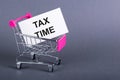 TAX TIME text on white sticky in a shopping trolley, gray background Royalty Free Stock Photo