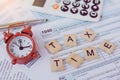 Tax time with wooden alphabet blocks, red alarm clock, calculator and pen on 1040 tax form backgrounda Royalty Free Stock Photo