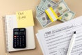 Tax Time written on yellow sticker, calculator, dollar banknote